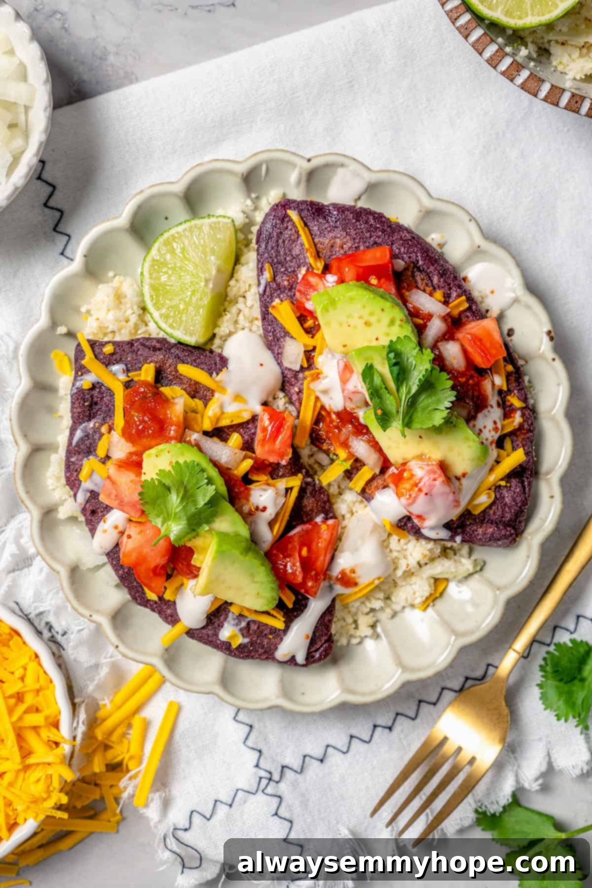 Easy tlacoyos filled with black beans. Top this homemade and vegan spin on Mexican street food with diced avocado, salsa and vegan cheese. Two tlacoyos on a plate.