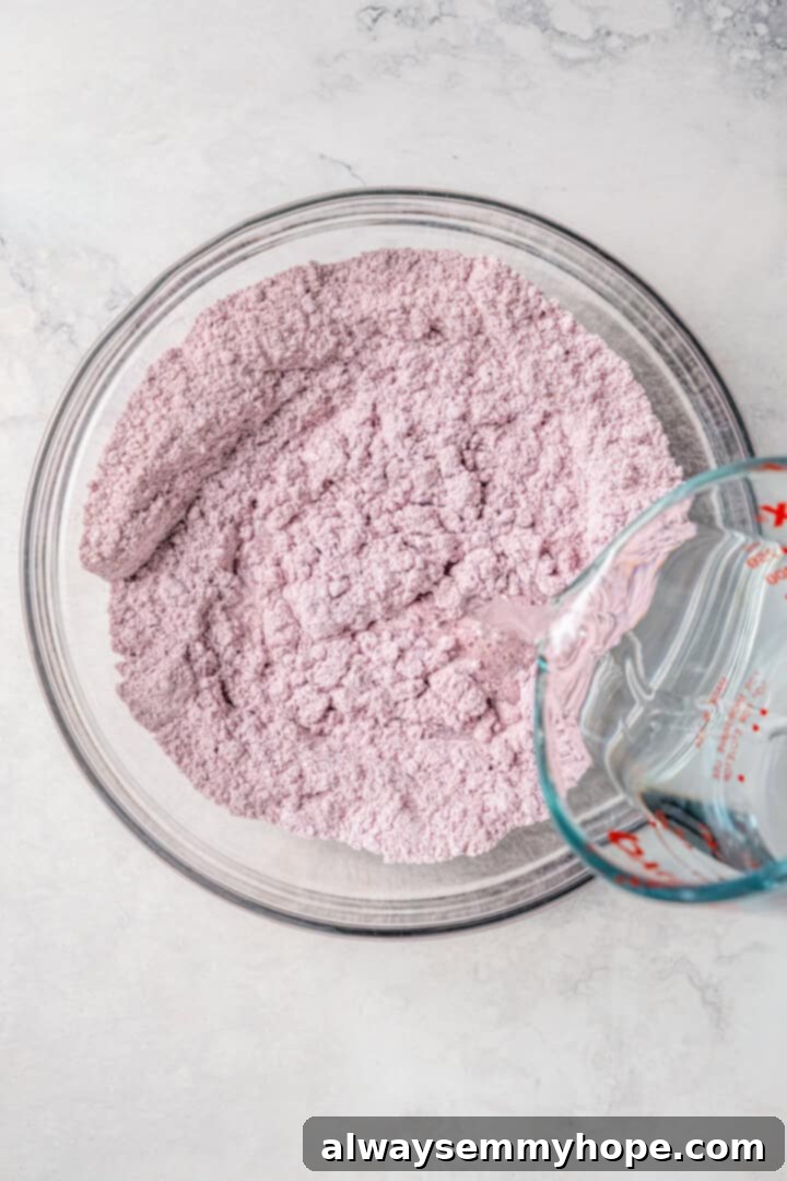 Easy tlacoyos filled with black beans. Top this homemade and vegan spin on Mexican street food with diced avocado, salsa and vegan cheese. Adding water to blue masa harina in a glass bowl.