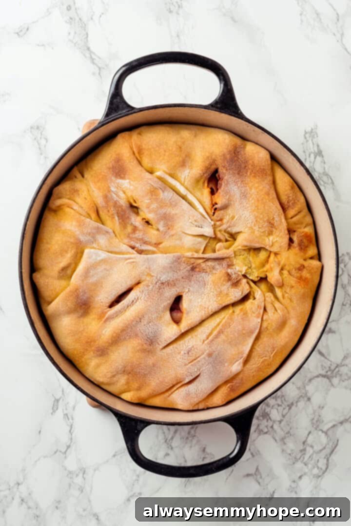 This vegan timpano recipe is perfect for the holidays! It’s loaded with pasta, veggies and plant-based cheese, all baked in a pastry crust. Overhead view of a perfectly baked vegan timpano, removed from the oven, with a golden-brown and firm crust, showcasing its readiness to be served.