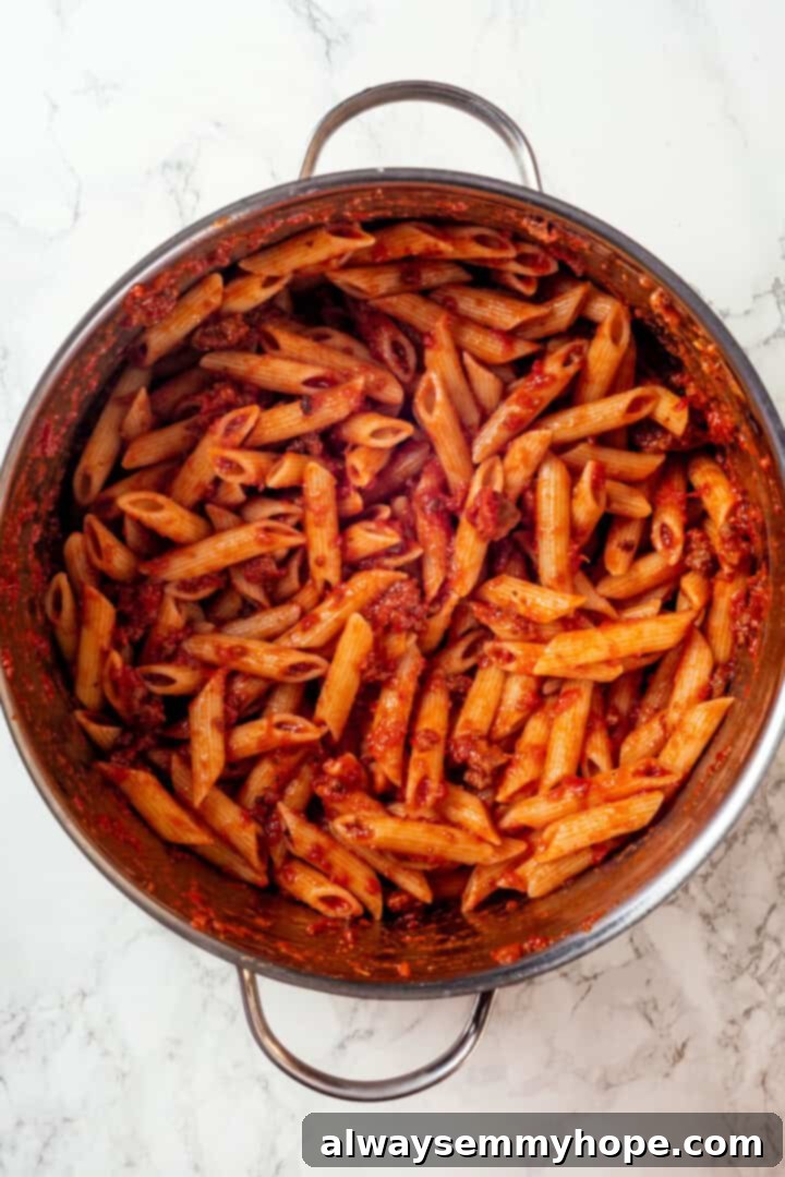 This vegan timpano recipe is perfect for the holidays! It’s loaded with pasta, veggies and plant-based cheese, all baked in a pastry crust. Cooked penne pasta mixed thoroughly with a rich marinara sauce, ready to be layered into the timpano.