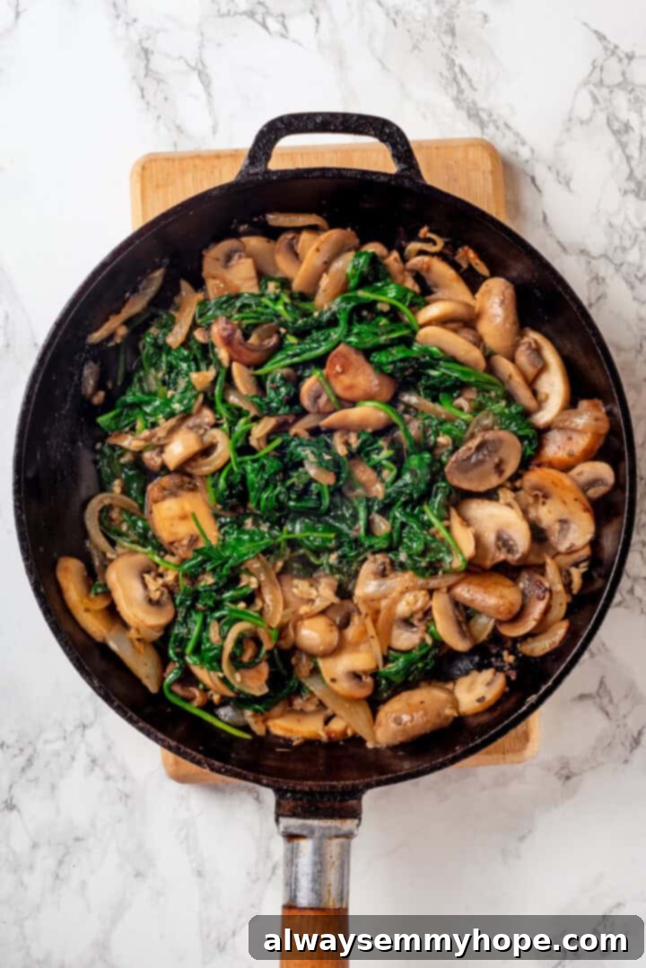 This vegan timpano recipe is perfect for the holidays! It’s loaded with pasta, veggies and plant-based cheese, all baked in a pastry crust. Sautéed mixture of mushrooms, onions, and spinach in a large skillet, wilted and aromatic.