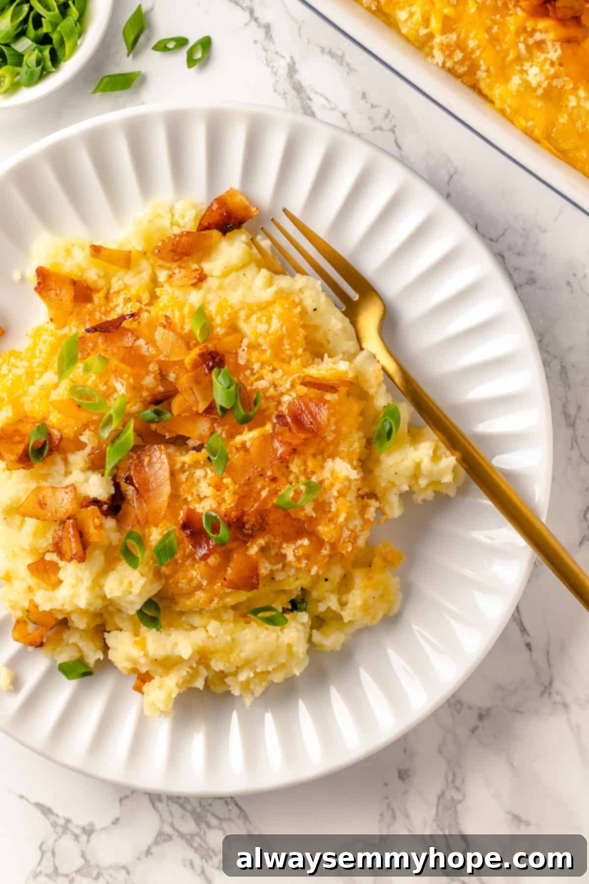 Mashed potato casserole is a comfort food side that’s always a crowd-pleaser! Vegan cheddar, bacon, and crispy panko make it extra delicious. Overhead view of mashed potato casserole on plate