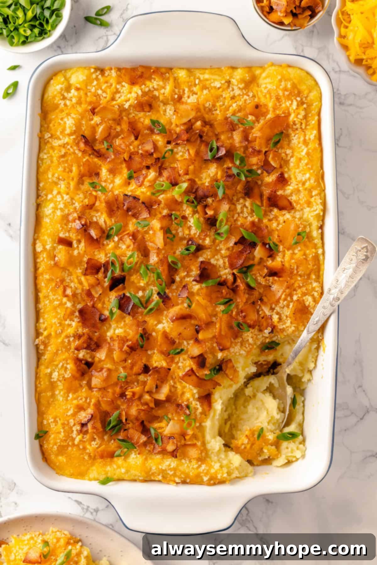Overhead view of a baked vegan mashed potato casserole in a baking dish, with a serving spoon taking a scoop
