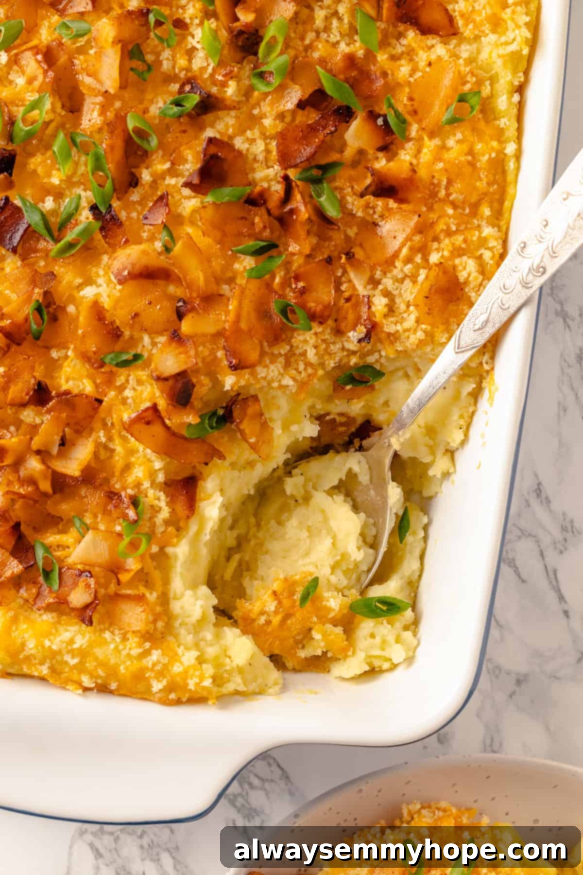 Overhead view of a baked vegan mashed potato casserole in a baking dish, garnished with green onions and vegan bacon
