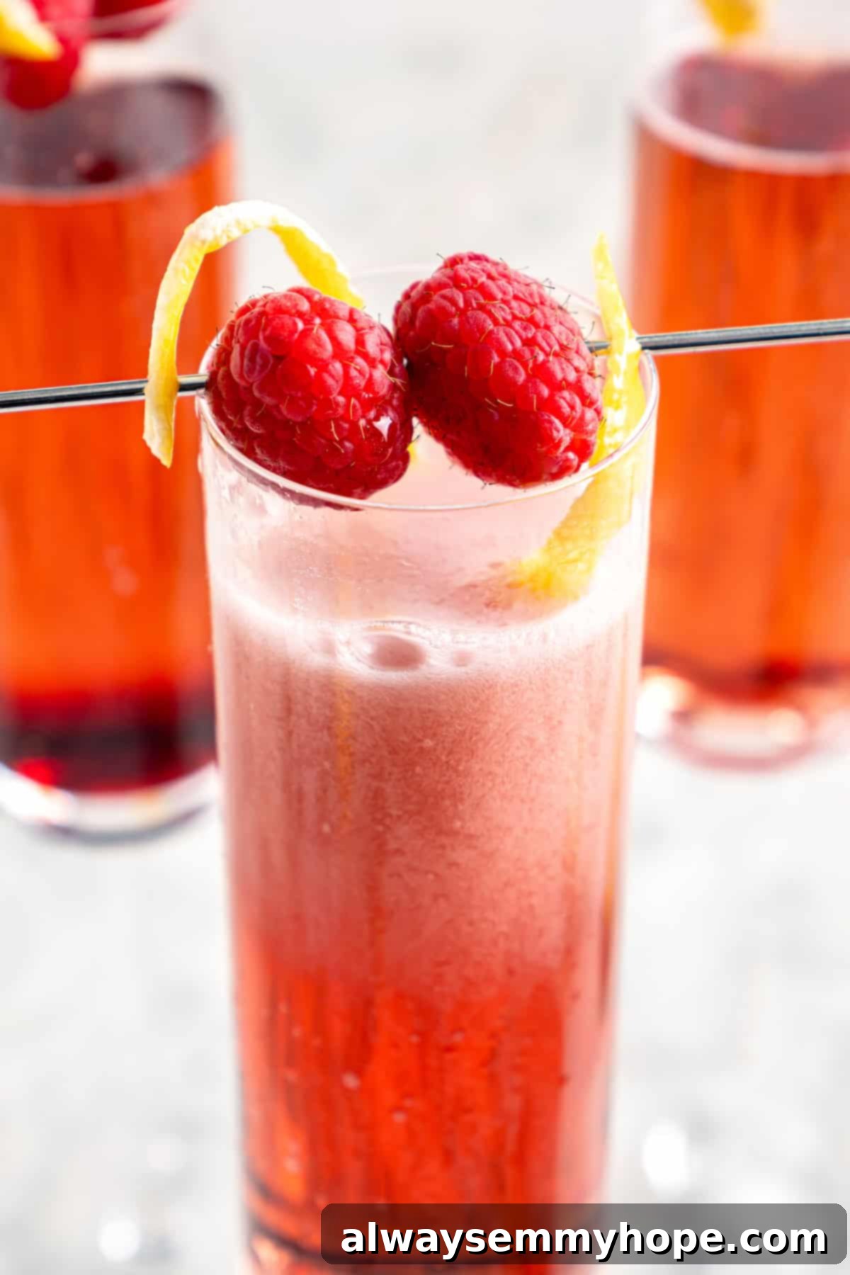 Kir Royale cocktail garnished with fresh raspberries and a delicate lemon twist, served in an elegant flute.