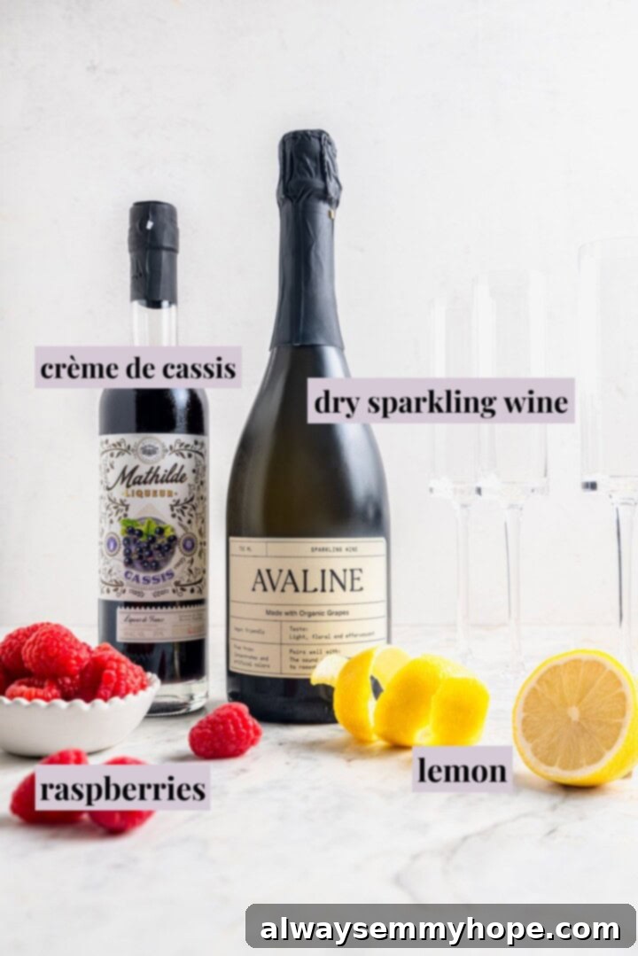 All the essential ingredients for a Kir Royale laid out on a clean marble counter: a bottle of sparkling wine, crème de cassis, and fresh raspberries.