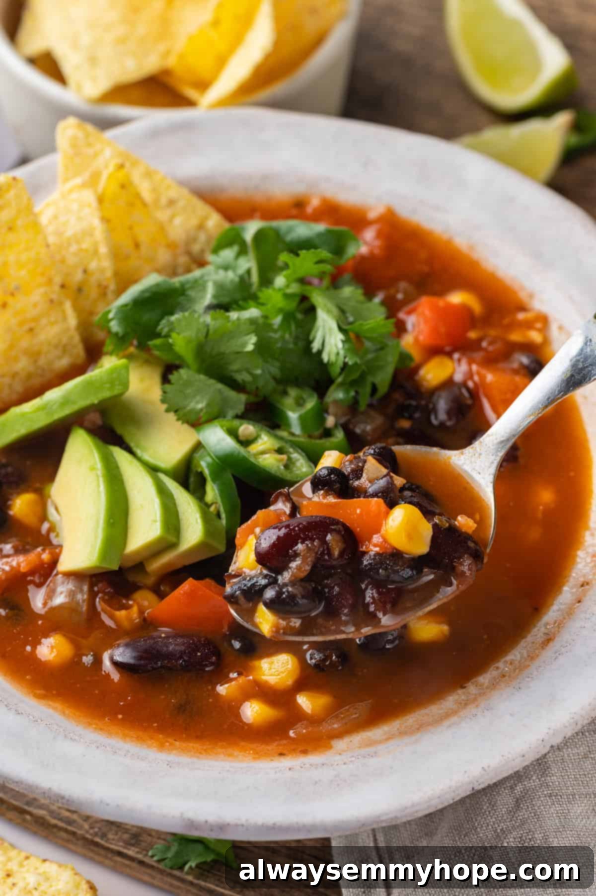 This vegan taco soup packs in a whole lot of flavour! With a zesty broth, lots of beans, and veggies, this soup is hearty and satisfying. Spoonful of taco soup held over bowl
