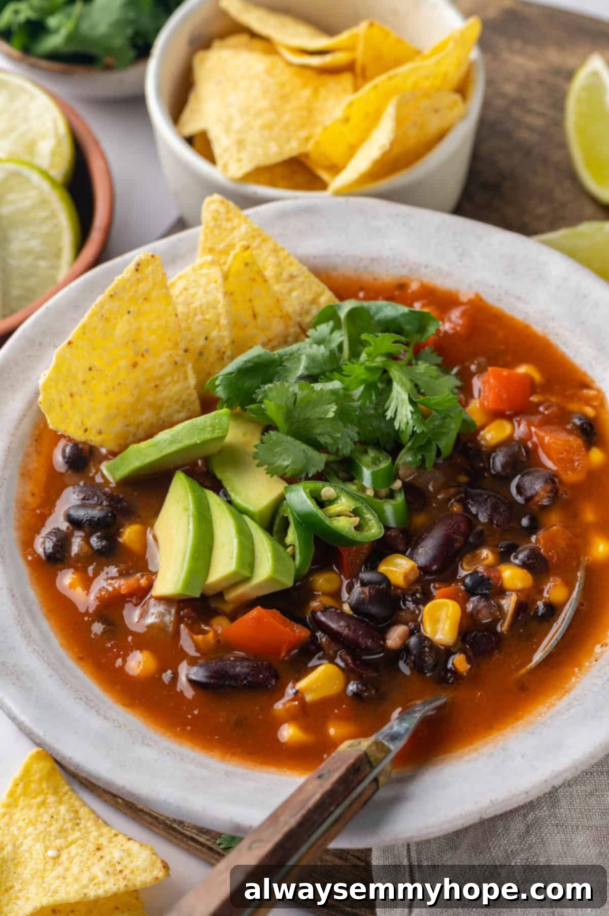 This vegan taco soup packs in a whole lot of flavour! With a zesty broth, lots of beans, and veggies, this soup is hearty and satisfying. Bowl full of taco soup with spoon
