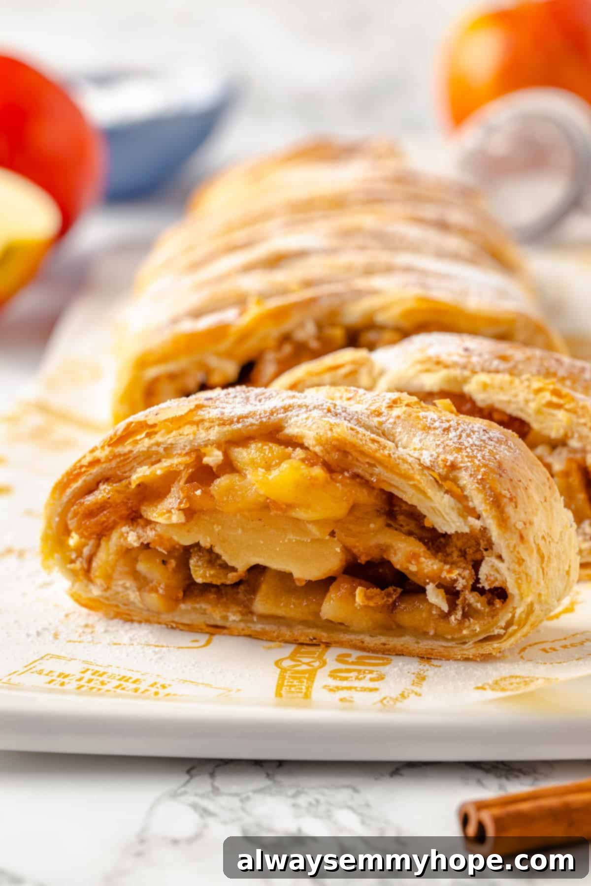 This easy apple strudel recipe wraps tender cinnamon-spiced apples in flaky puff pastry for a cozy treat. It's always a hit! Sliced vegan apple strudel on cutting board, with serving tongs