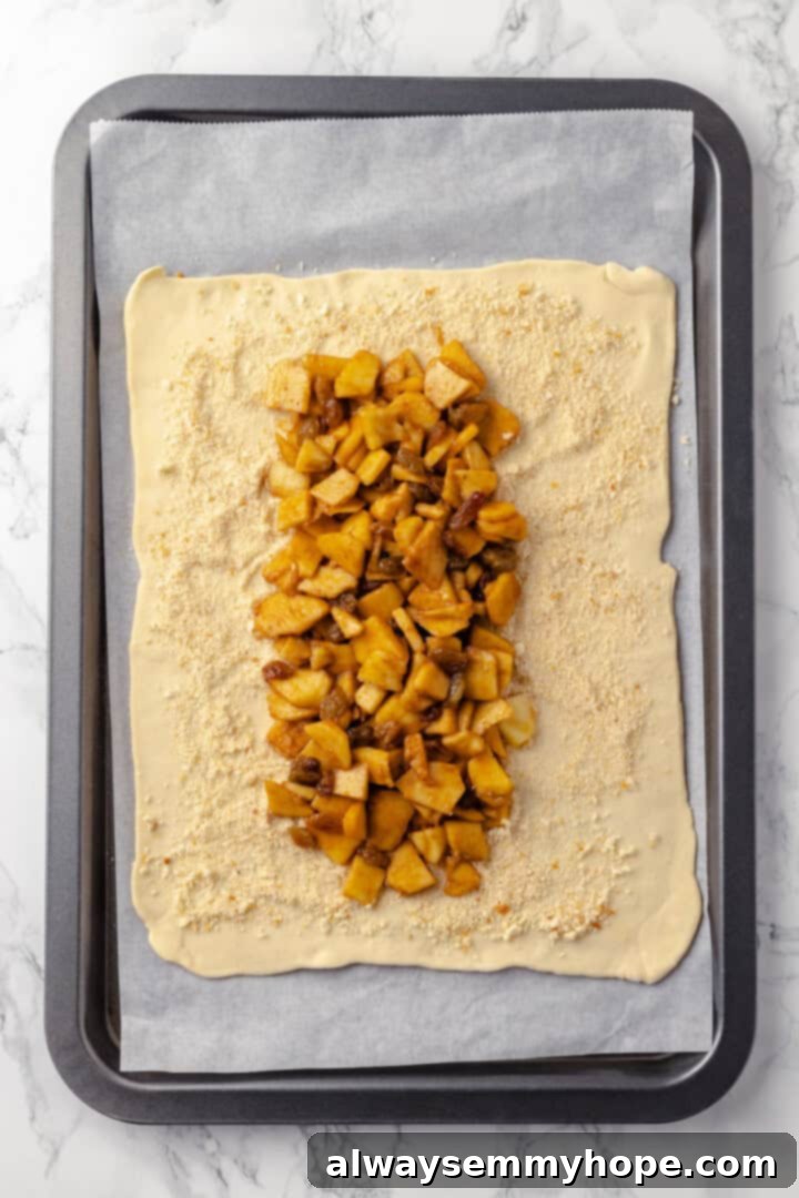 This easy apple strudel recipe wraps tender cinnamon-spiced apples in flaky puff pastry for a cozy treat. It's always a hit! Overhead view of filling added to puff pastry sheet