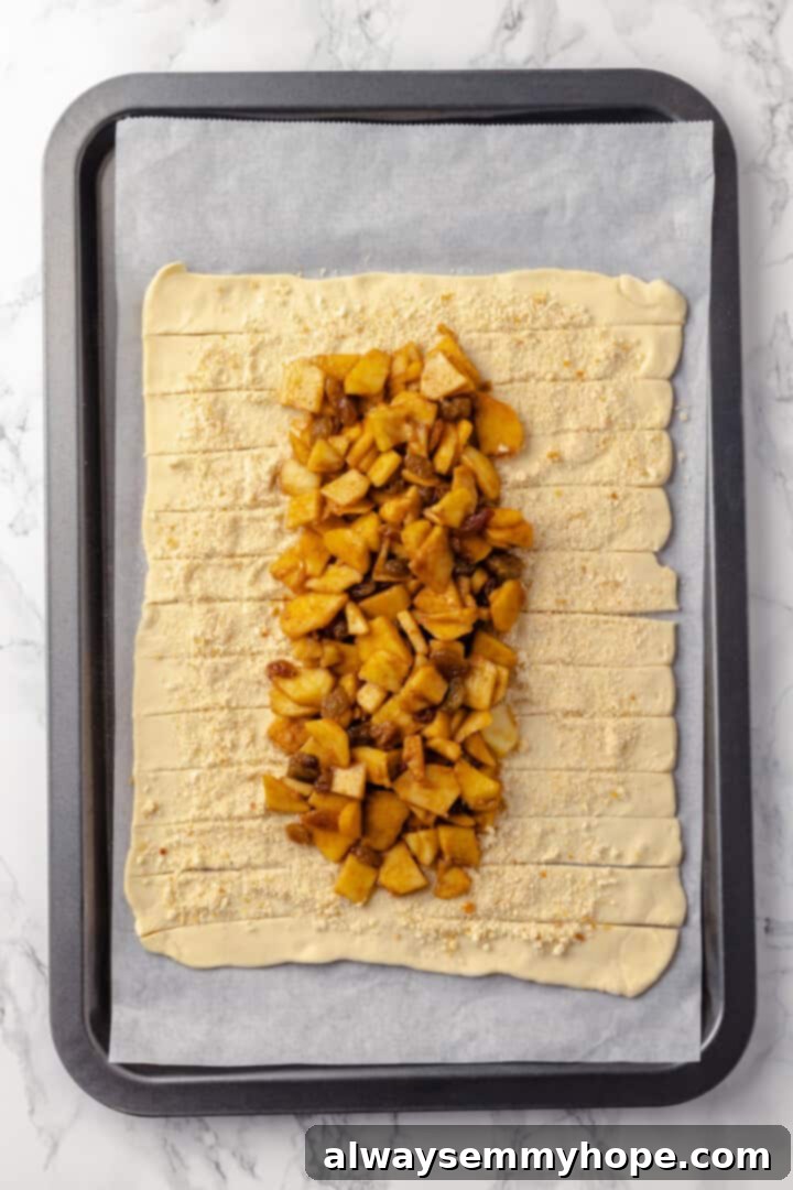 This easy apple strudel recipe wraps tender cinnamon-spiced apples in flaky puff pastry for a cozy treat. It's always a hit! Overhead view of apple strudel with pastry cut into strips