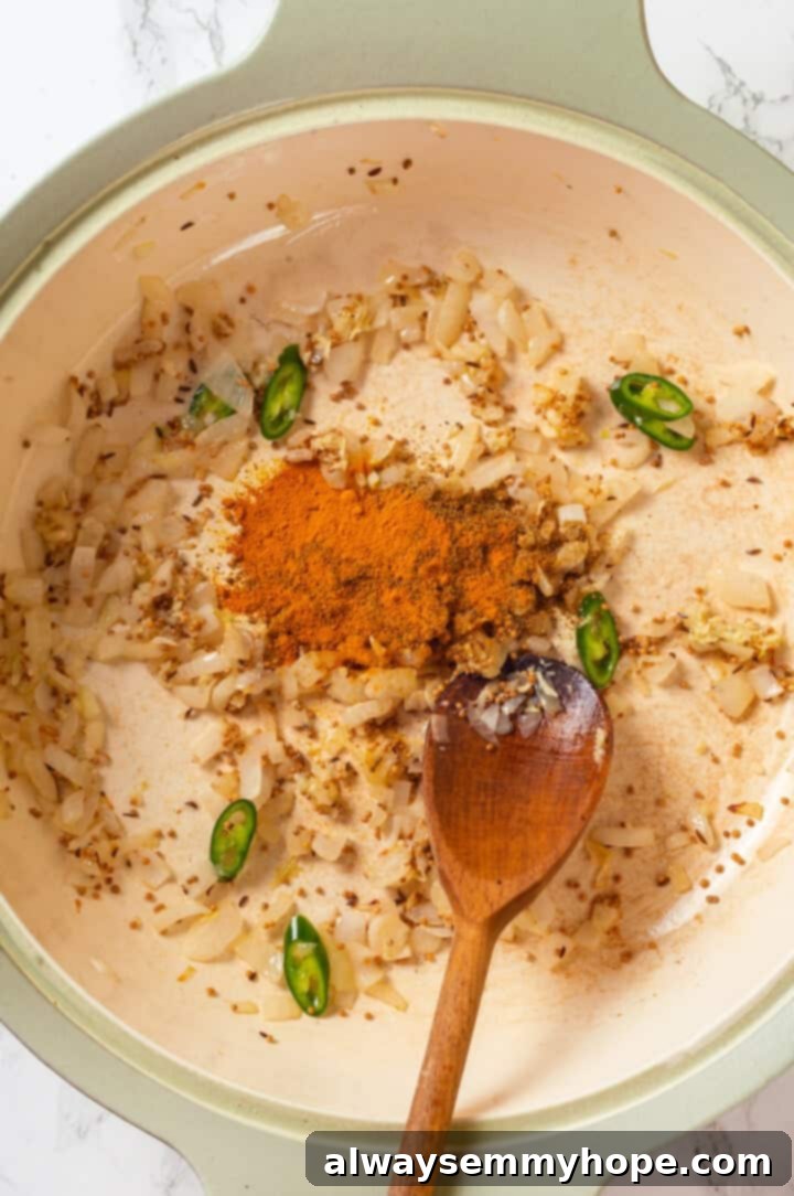 Sautéing Aromatics and Ground Spices Finely chopped onions, minced garlic, ginger, and green chilies, along with vibrant ground spices like turmeric, cumin, and coriander, sautéing in a pan to create a fragrant base for the dal.