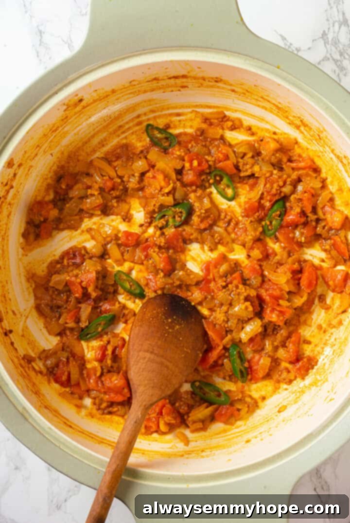 Adding Tomatoes to the Spice Mixture Chopped fresh tomatoes being stirred into the fragrant spice and aromatic mixture in a pan, slowly softening and integrating into the dal's base.