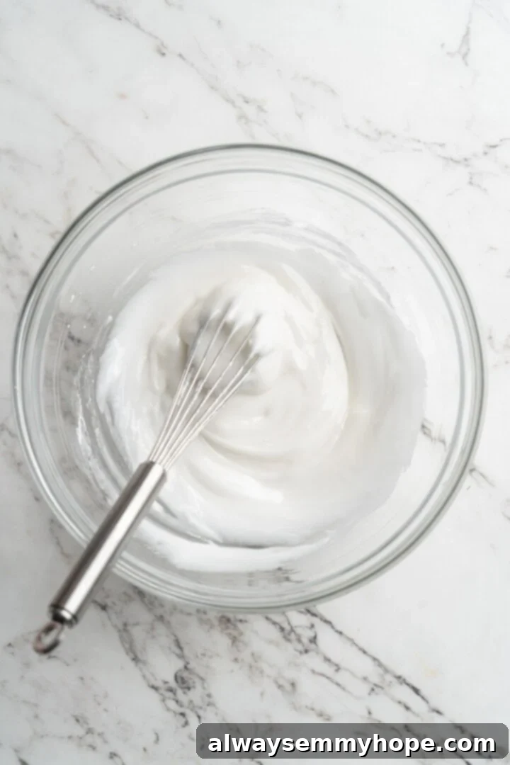 A hand whisking powdered sugar and water together in a glass bowl to create the base for homemade sprinkles.