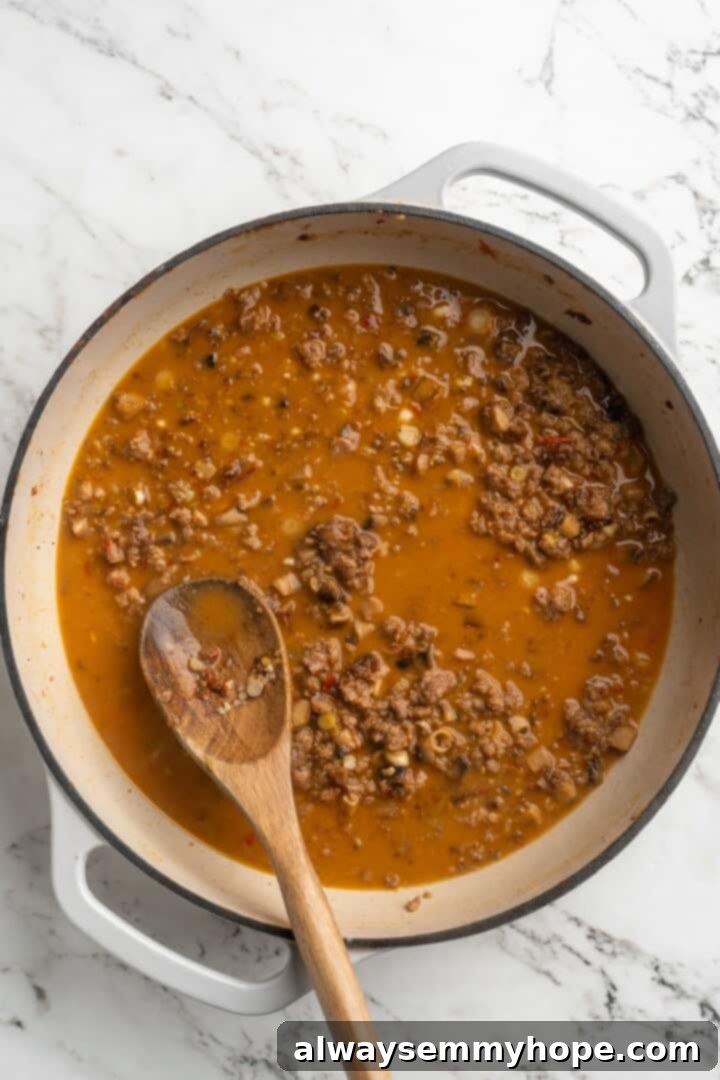 Building the spicy and savory Mapo Tofu sauce The rich, reddish Mapo Tofu sauce simmering in a skillet, thickened and glossy.