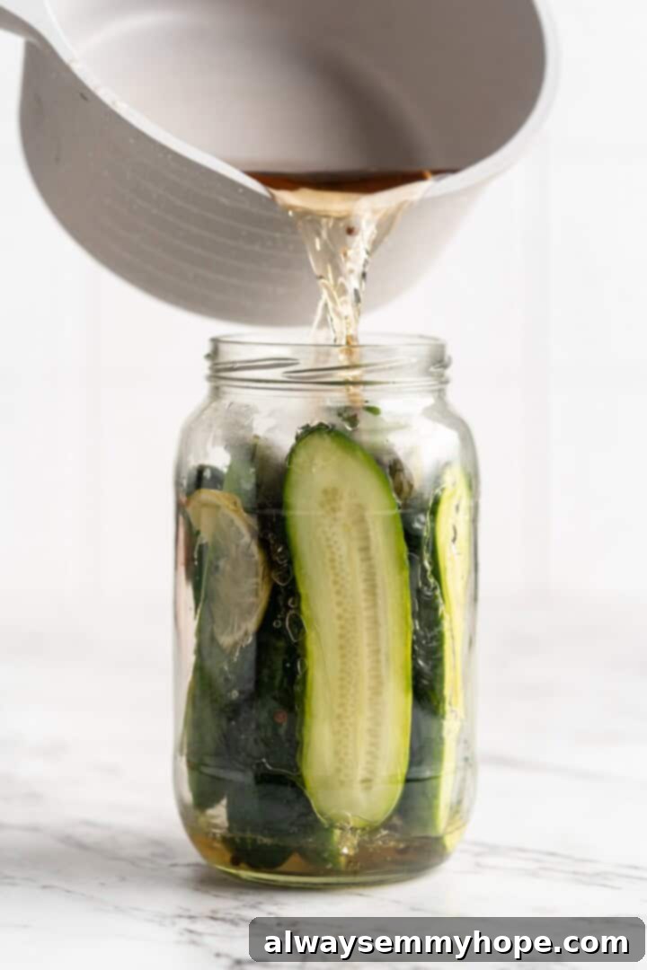 Hot brine being carefully poured over the cucumbers in a mason jar.