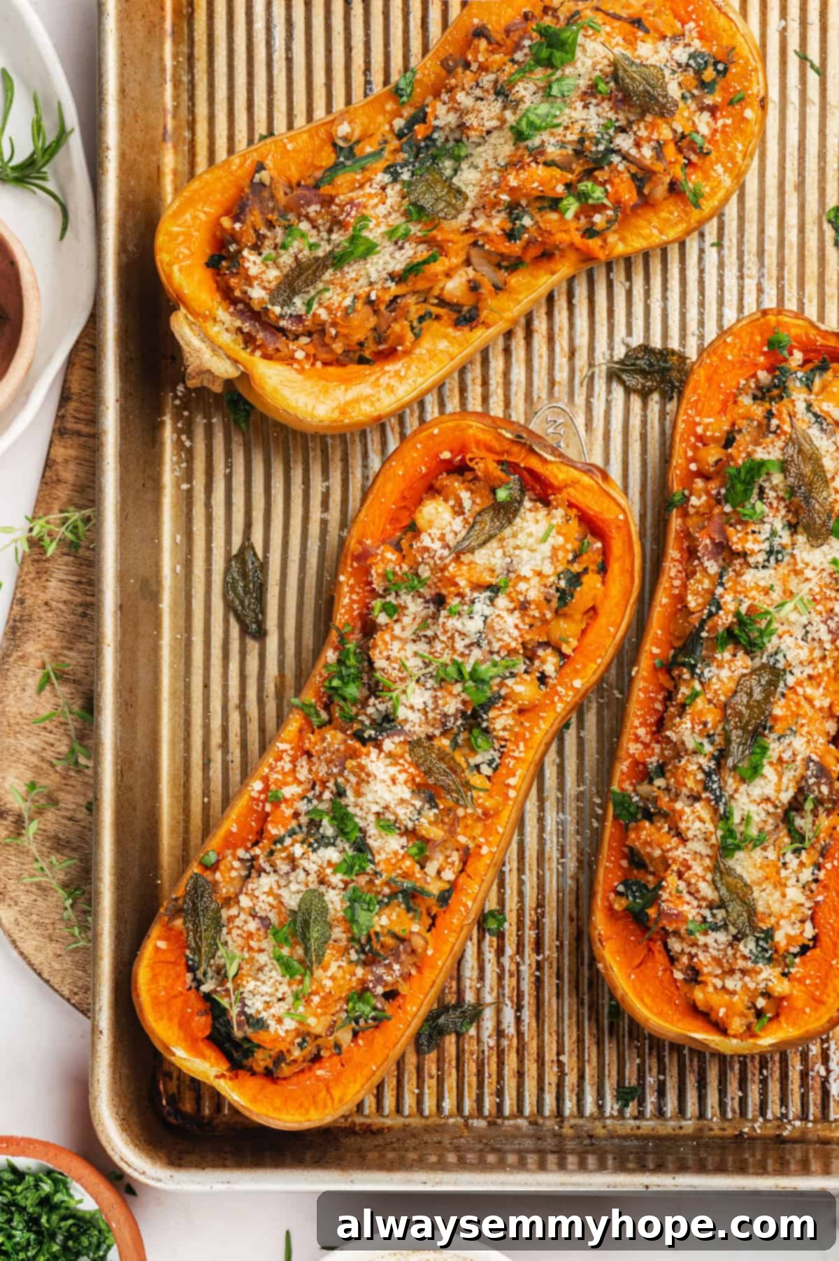 Vegan stuffed butternut squash on sheet pan, garnished with herbs