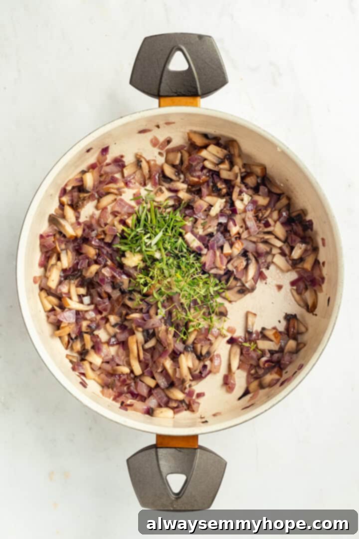 Red onion, mushrooms, and herbs sizzling in a pan