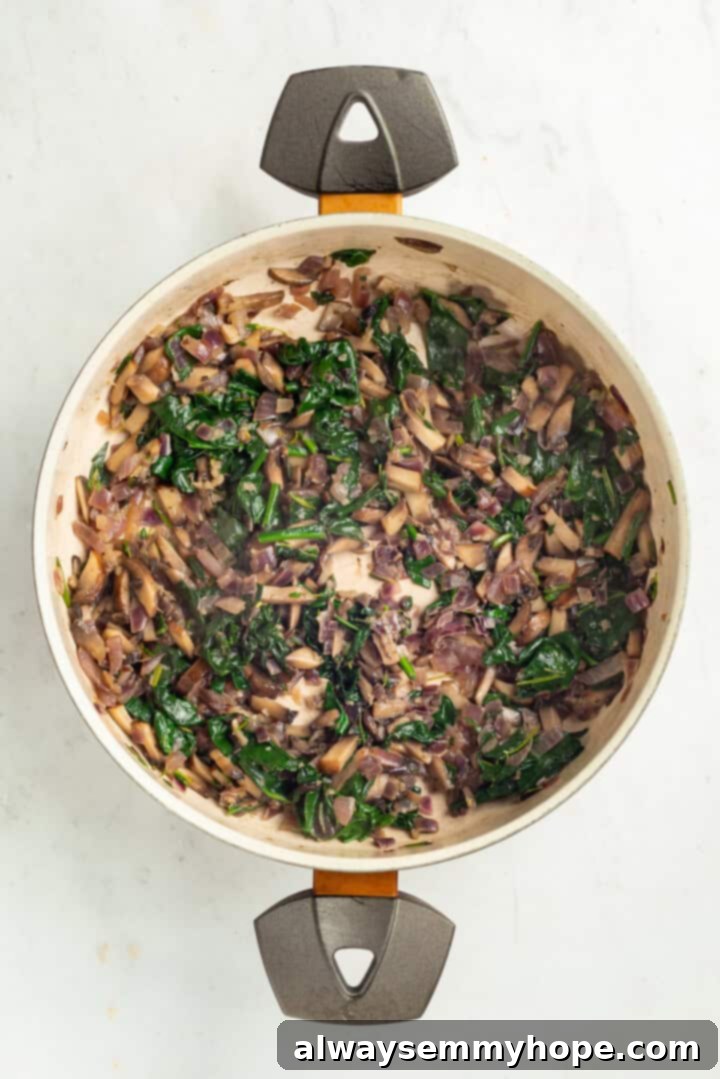 Spinach being stirred into the mushroom and onion mixture in a pan