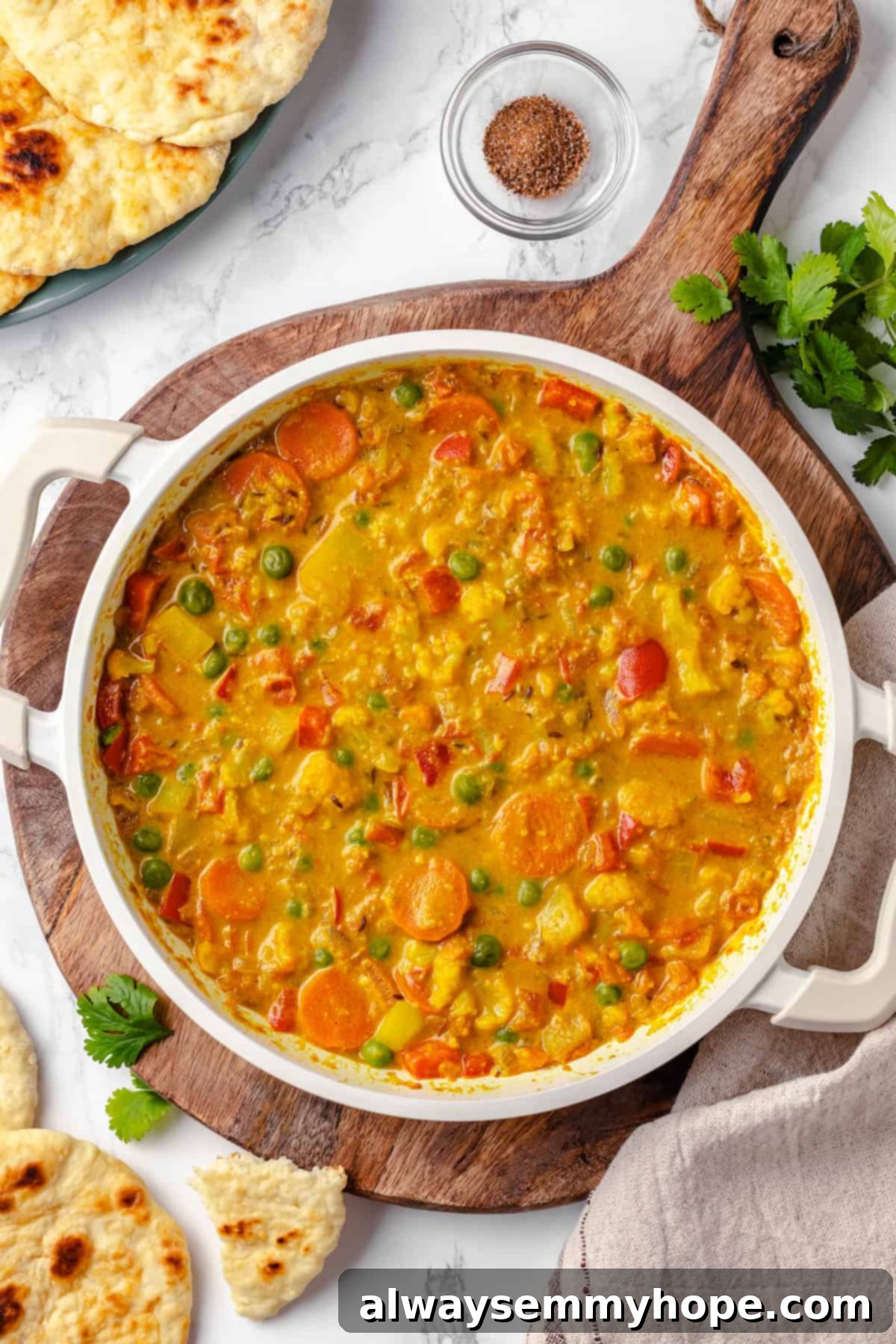 Vegetable korma is a rich and creamy Indian curry loaded with warm spices and tender veggies. It’s absolutely decadent and so easy to make! Pan of vegetable korma on wooden board