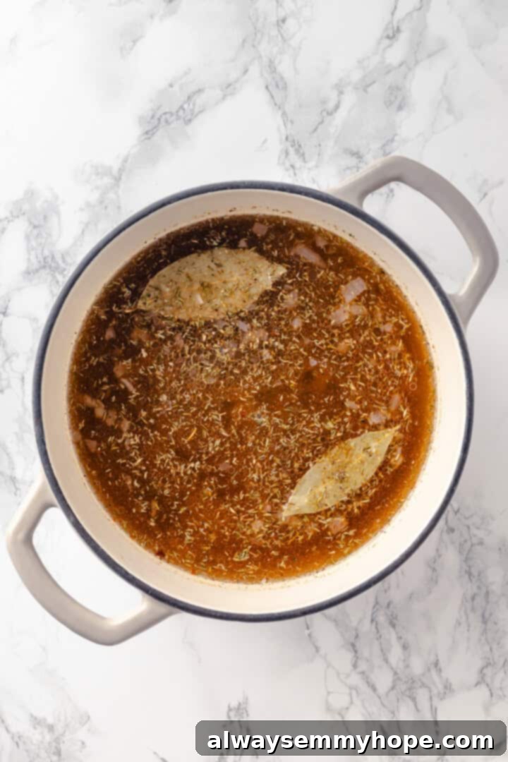 A pot filled with vegetable broth, dried split peas, bay leaves, dried thyme, and smoked paprika, simmering gently on the stovetop.