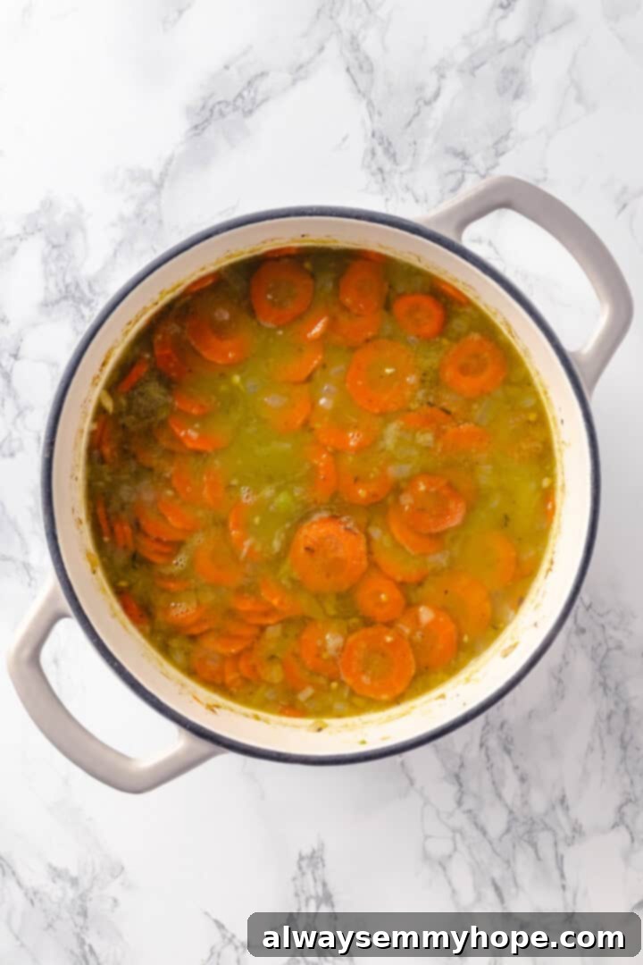 Chopped carrots and diced potatoes being added to a simmering pot of vegan split pea soup, enhancing its color and texture.