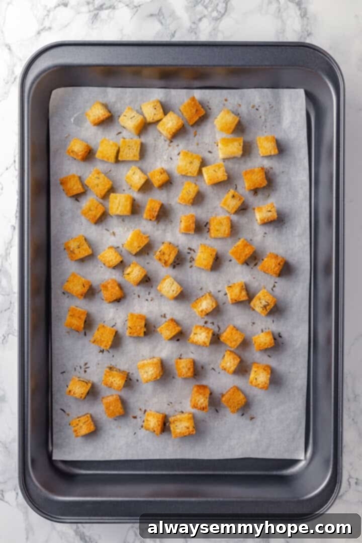 Golden-brown, crispy homemade croutons spread on a baking sheet, freshly baked and ready to top the soup.