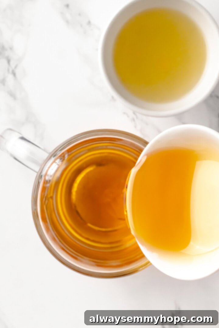 This hot toddy recipe will cure whatever ails you! It's a classic cocktail made with whiskey, lemon juice, and maple syrup to make it vegan. Pouring whiskey into a mug with maple syrup and lemon juice for a hot toddy