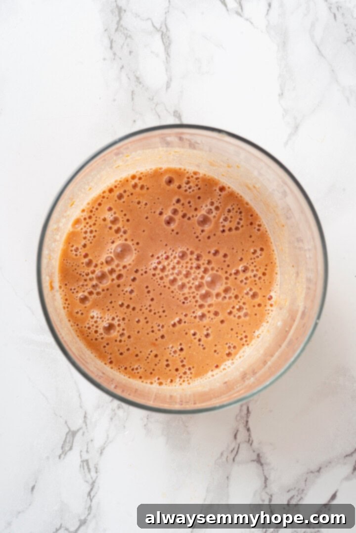 Blended cashews, broth, sun-dried tomatoes, and nutritional yeast creating a creamy, light orange sauce mixture for Marry Me Chickpeas.