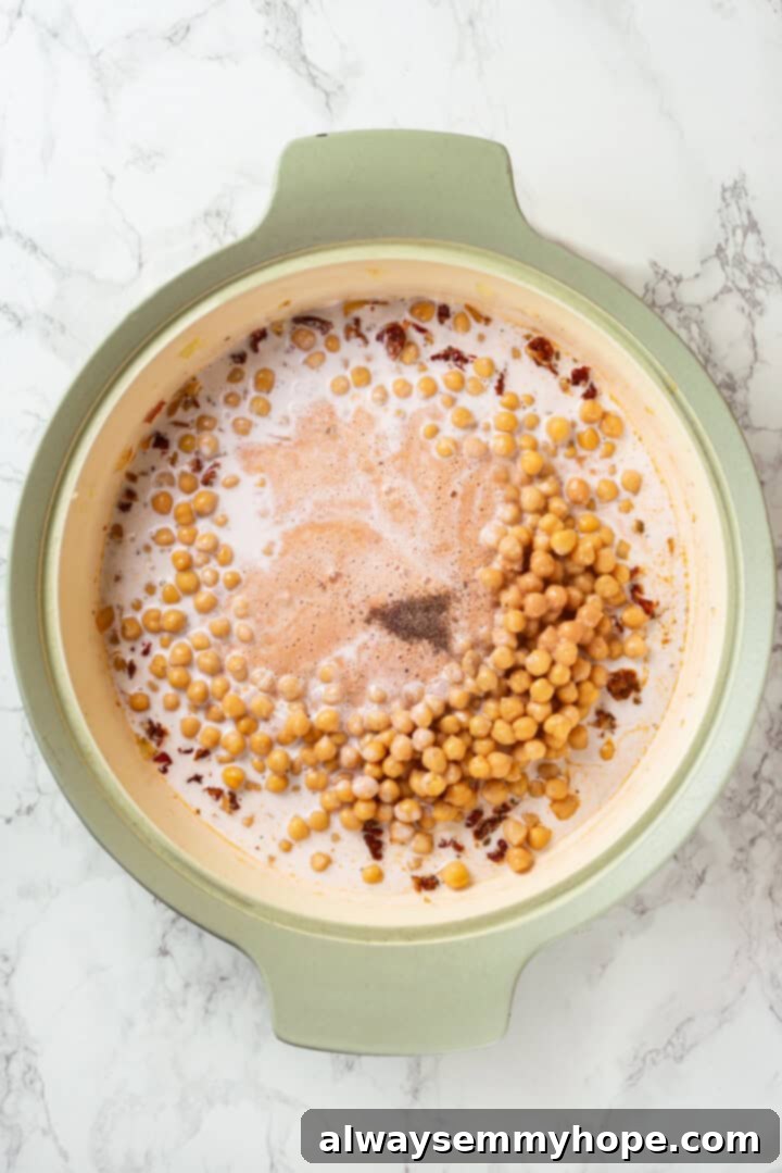 A pan filled with chickpeas, the cashew cream mixture, and coconut milk, ready to be simmered into creamy Marry Me Chickpeas.