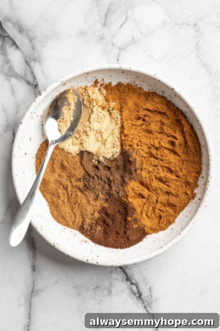 Overhead view of separate ingredients for pumpkin pie spice measured into a bowl before stirring.