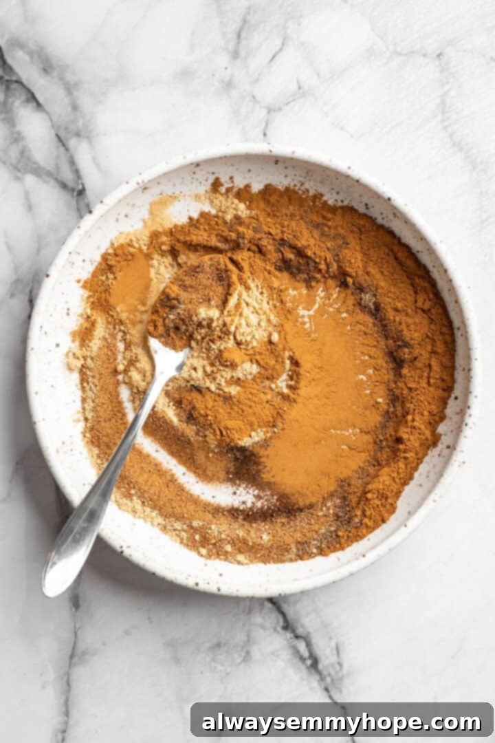 Spoon stirring pumpkin pie spice in bowl
