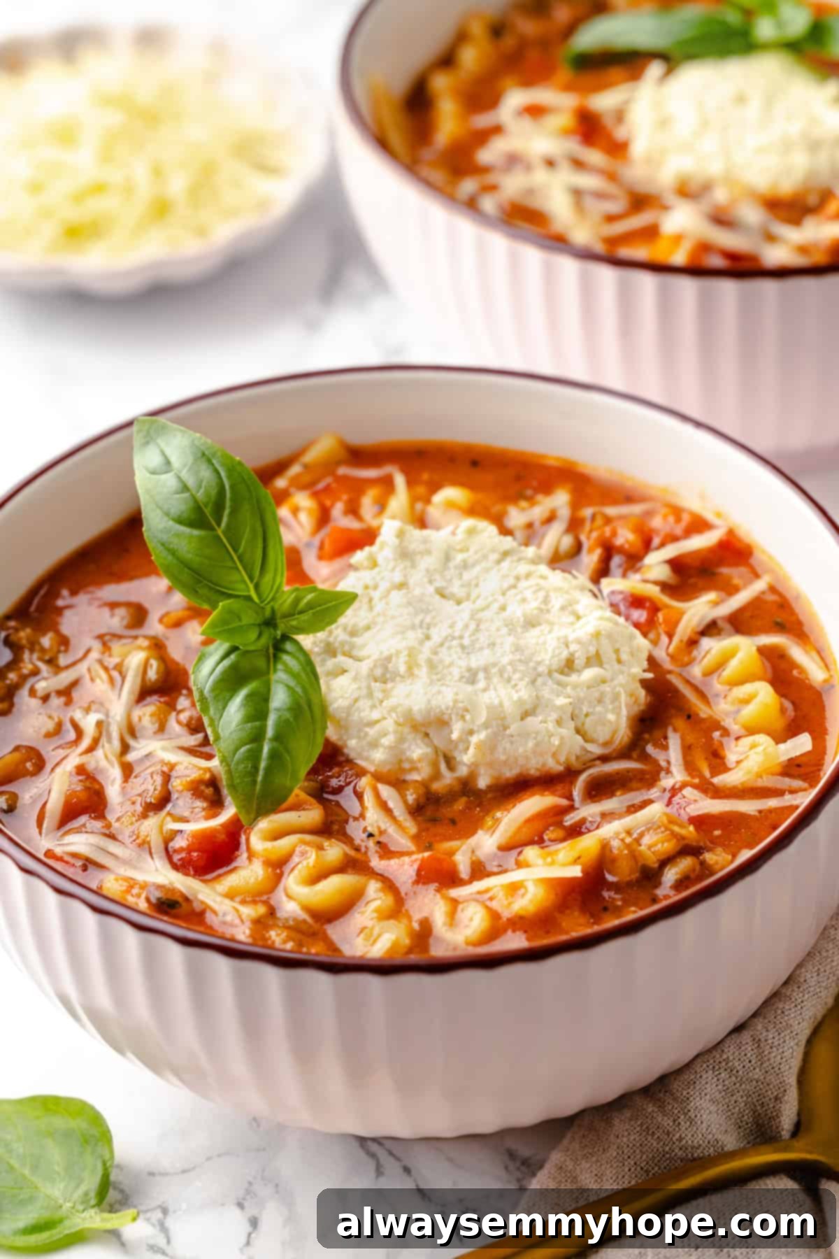 Enjoy two steaming bowls of this incredible vegan lasagna soup, rich with Italian-inspired flavours and a generous topping of vegan cheeses. A close-up of two warm bowls of vegan lasagna soup, garnished with fresh basil, ready for a comforting meal.