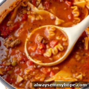Lasagna Soup 2 A ladle serving a generous portion of steaming hot vegan lasagna soup from a large pot, showing the noodles and rich broth.