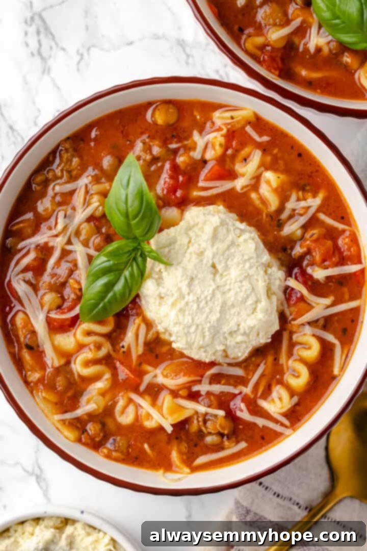 Serve the hot lasagna soup in bowls, adding a generous portion of the cheesy topping for ultimate indulgence. Close-up overhead view of a single bowl of vegan lasagna soup, generously topped with melted vegan cheeses and fresh basil, ready to be enjoyed.