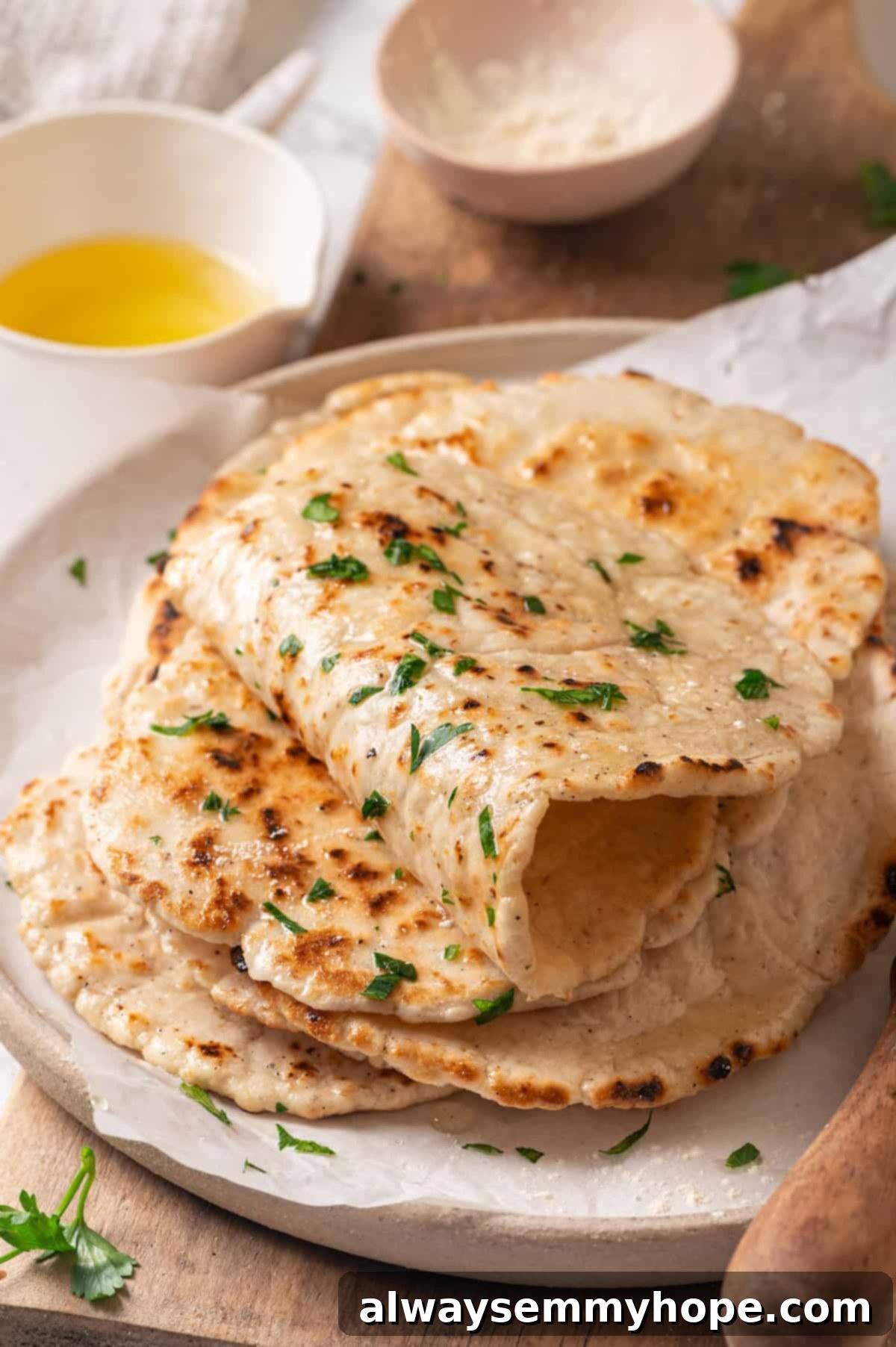 This easy gluten-free naan recipe has the chewy texture and slightly charred bits that make naan so irresistible, but without the wheat! A beautifully stacked pile of homemade gluten-free naan bread on a plate, ready to be enjoyed with Indian cuisine.