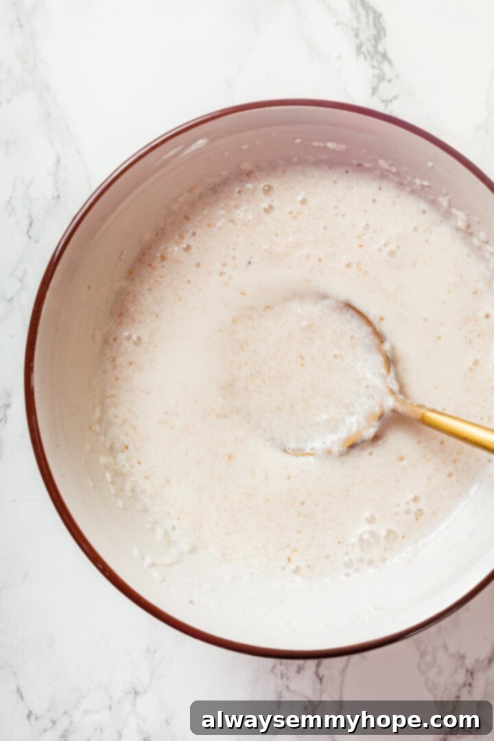 This easy gluten-free naan recipe has the chewy texture and slightly charred bits that make naan so irresistible, but without the wheat! A small bowl showing the psyllium husk, vegan milk, and yogurt mixture gelling and thickening, preparing for the naan dough.