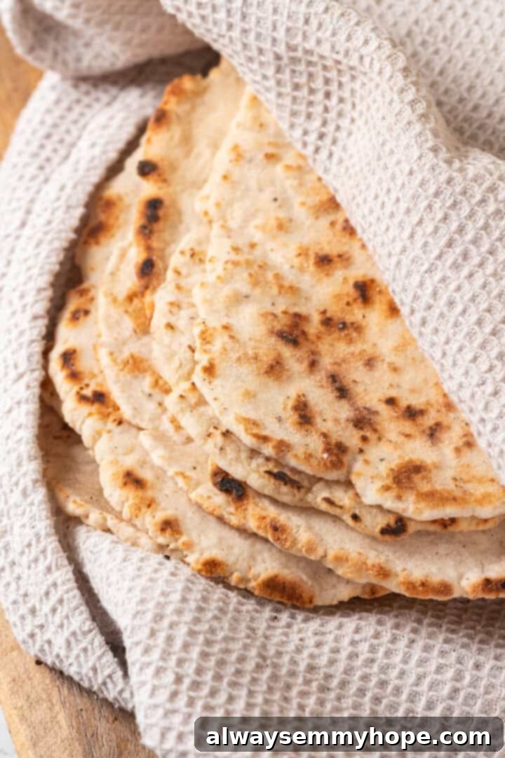 This easy gluten-free naan recipe has the chewy texture and slightly charred bits that make naan so irresistible, but without the wheat! Cooked gluten-free naan wrapped in a clean kitchen towel to keep it warm and soft.