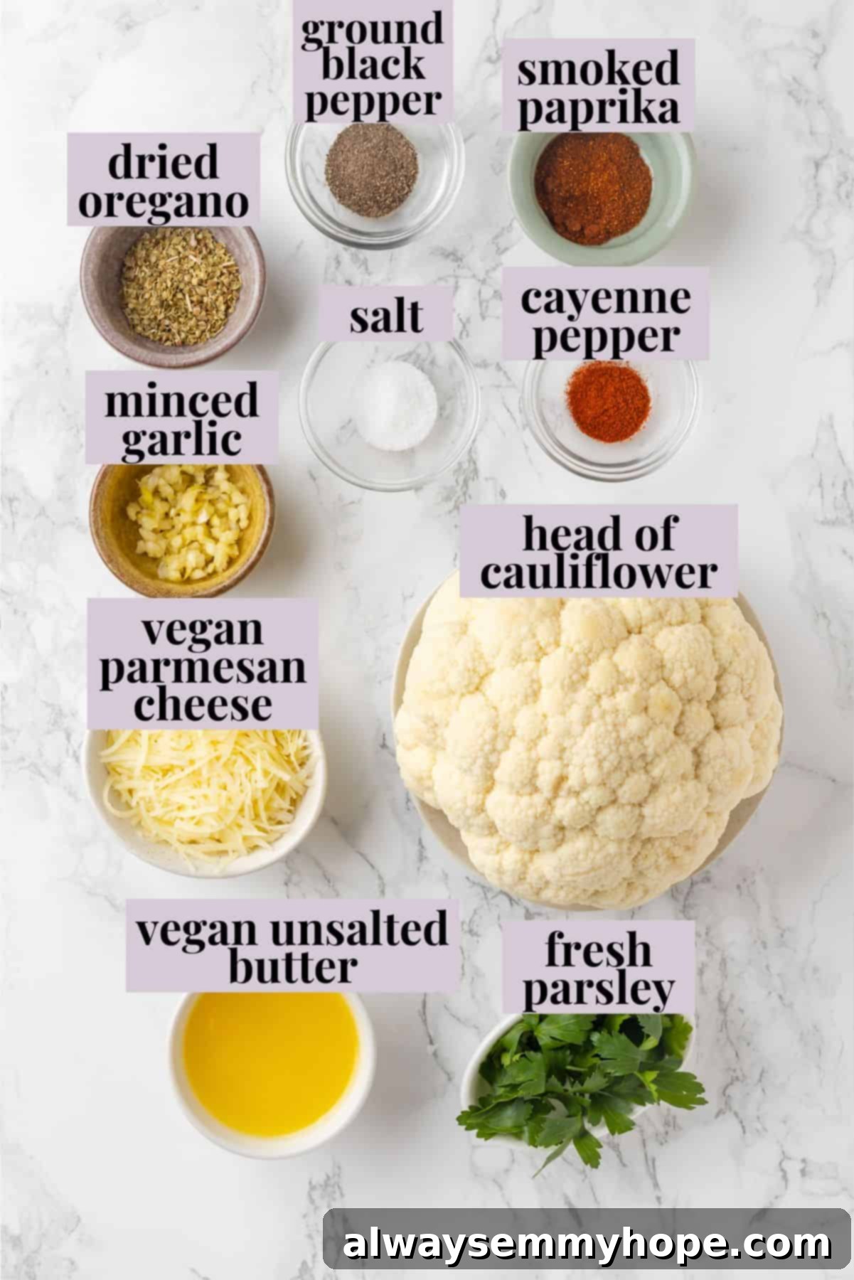 An overhead view of all the fresh ingredients laid out, ready for making whole roasted cauliflower, including a head of cauliflower, vegan butter, garlic, and various spices.