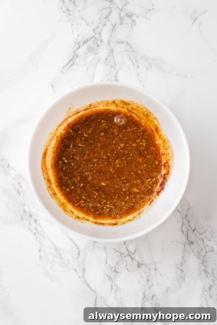 A small bowl containing a golden, melted butter and seasoning mixture, ready to be brushed onto the cauliflower.