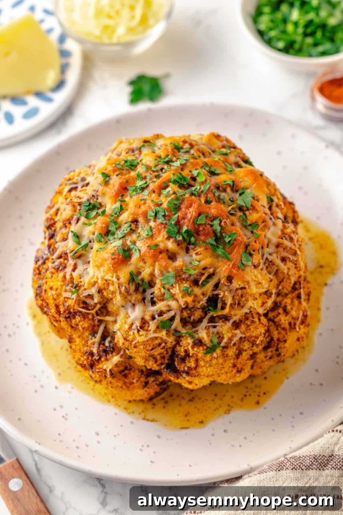 A single wedge of whole roasted cauliflower, beautifully seasoned and cooked, served on a white plate with a fork.