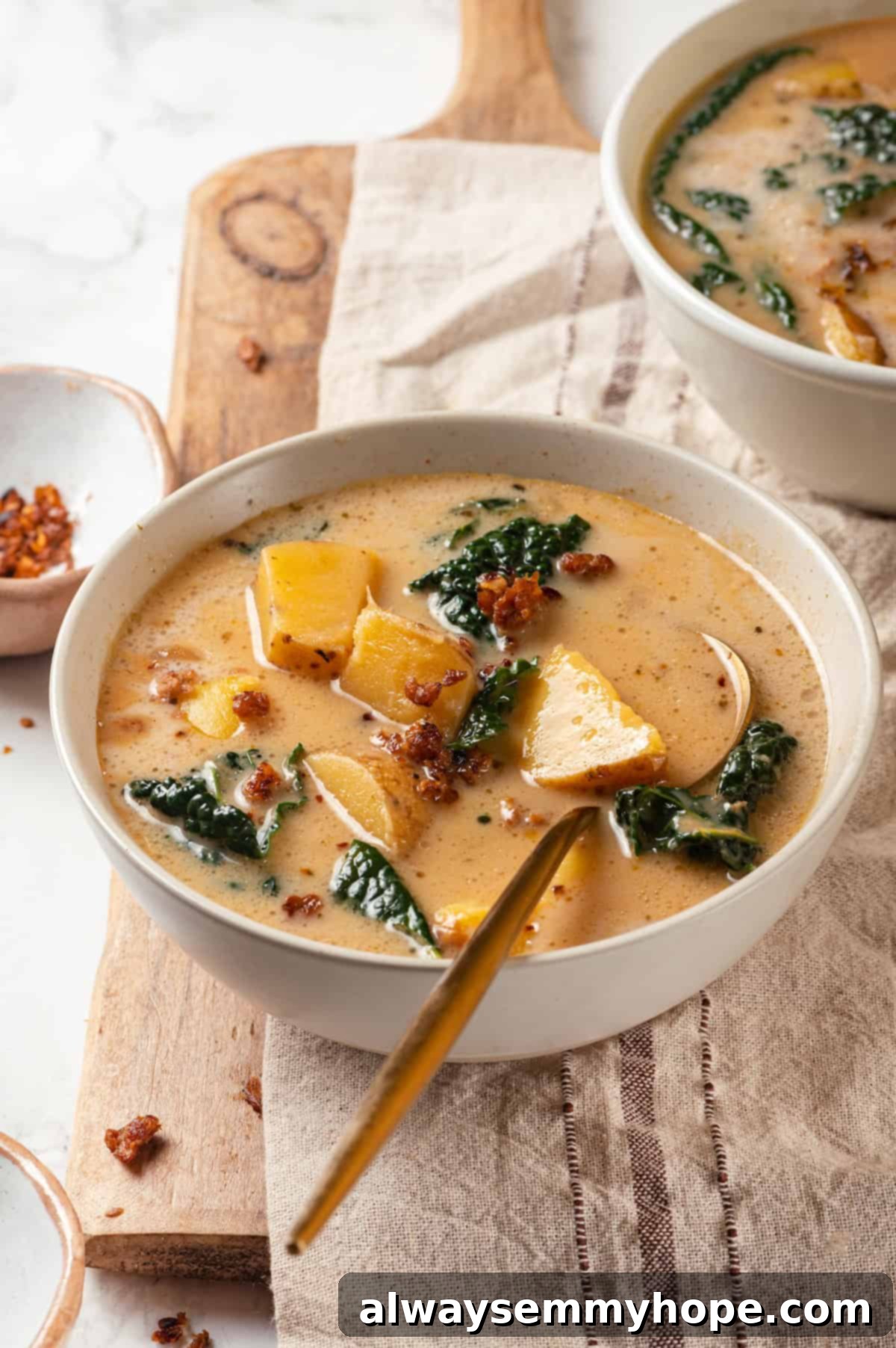 Two steaming bowls of creamy vegan Zuppa Toscana with fresh kale and sausage crumbles.