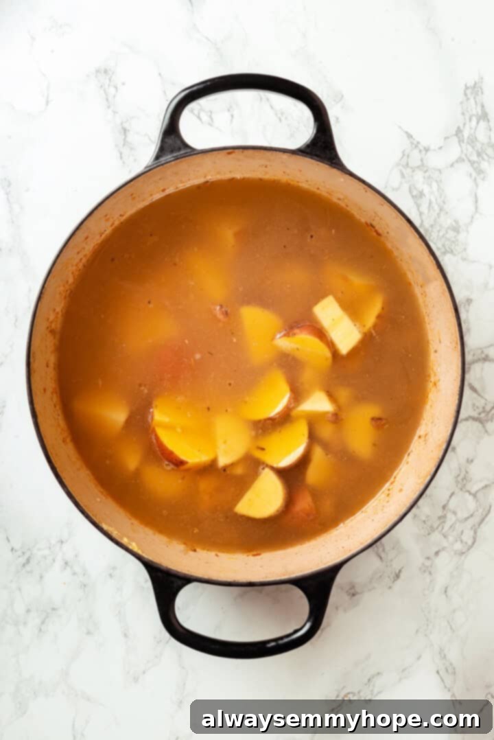 Diced Yukon Gold potatoes simmering in a pot of vegan Zuppa Toscana soup base.
