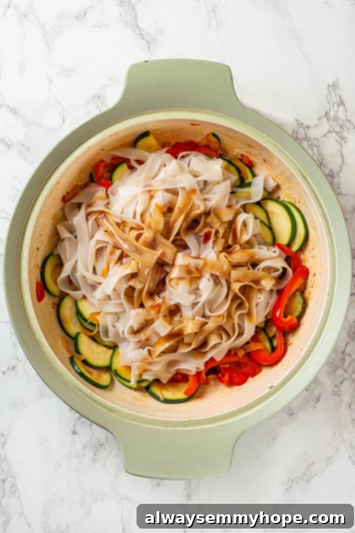This easy Thai drunken noodles recipe is a quick stir-fry dinner perfect for a weeknight. They're sweet, savoury, spicy—and vegan too! Noodles and sauce added to skillet with vegetables