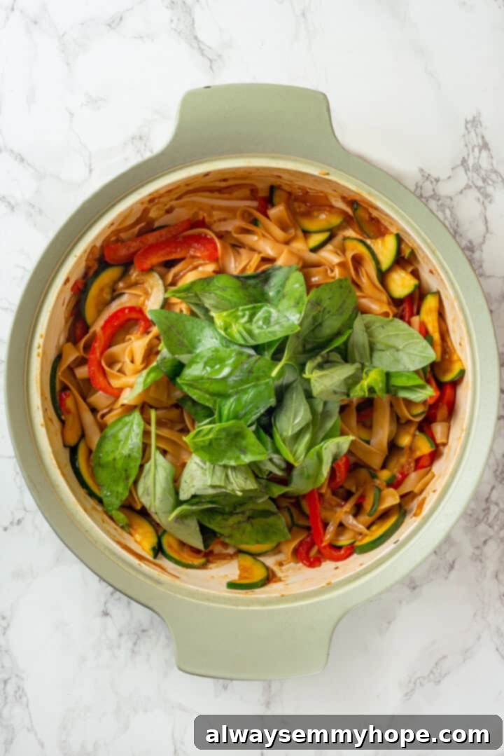 This easy Thai drunken noodles recipe is a quick stir-fry dinner perfect for a weeknight. They're sweet, savoury, spicy—and vegan too! Basil added to skillet of drunken noodles