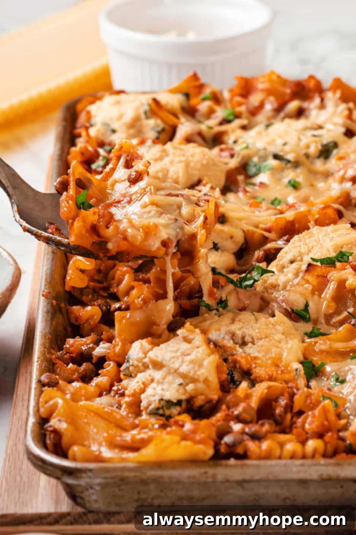 This vegan sheet pan lasagna recipe is a different way to enjoy all that cheesy pasta goodness—easier, quicker, and more crispy edges! A serving of crispy vegan sheet pan lasagna being carefully spooned from the baking pan.