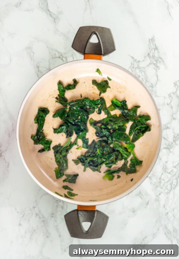 This vegan sheet pan lasagna recipe is a different way to enjoy all that cheesy pasta goodness—easier, quicker, and more crispy edges! Wilted spinach in a non-stick skillet, ready for the next step of the vegan sheet pan lasagna recipe.