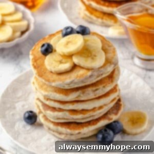 A stack of perfectly golden and fluffy vegan banana pancakes, with fresh berries on top