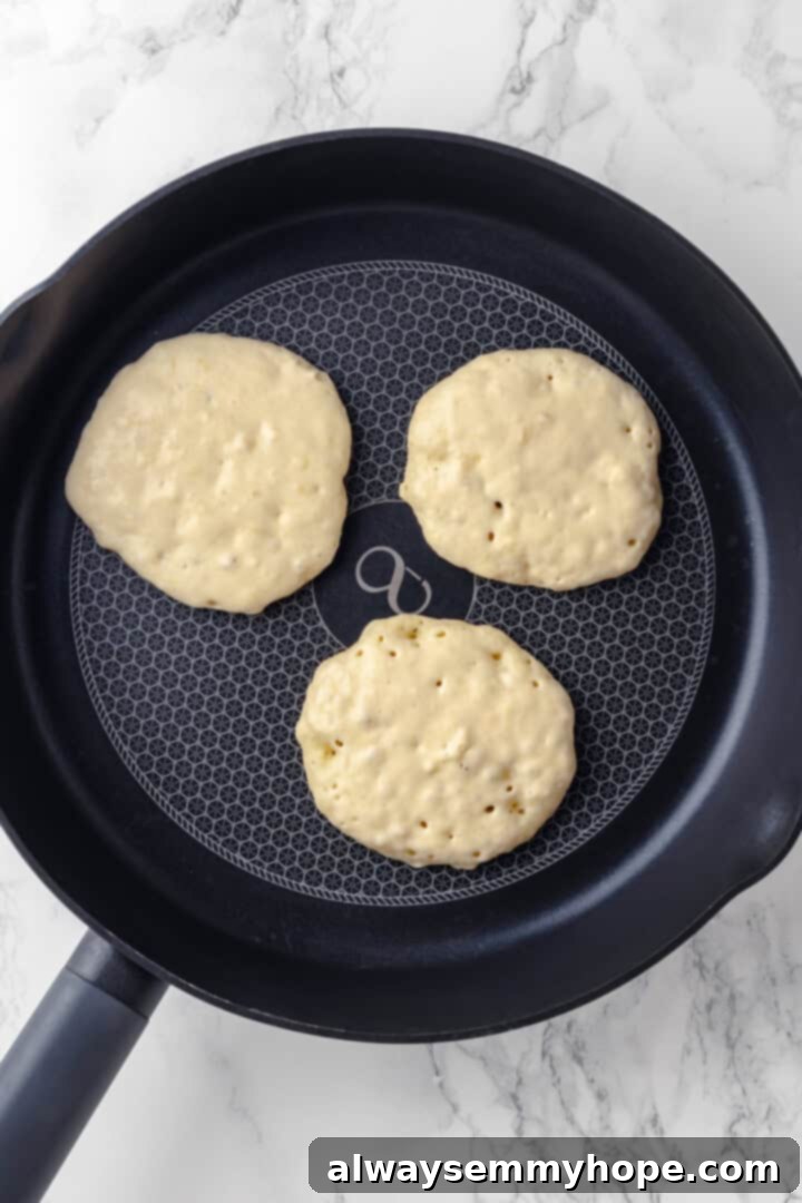 Vegan banana pancake batter poured into a hot skillet, showing early bubbles forming on the surface