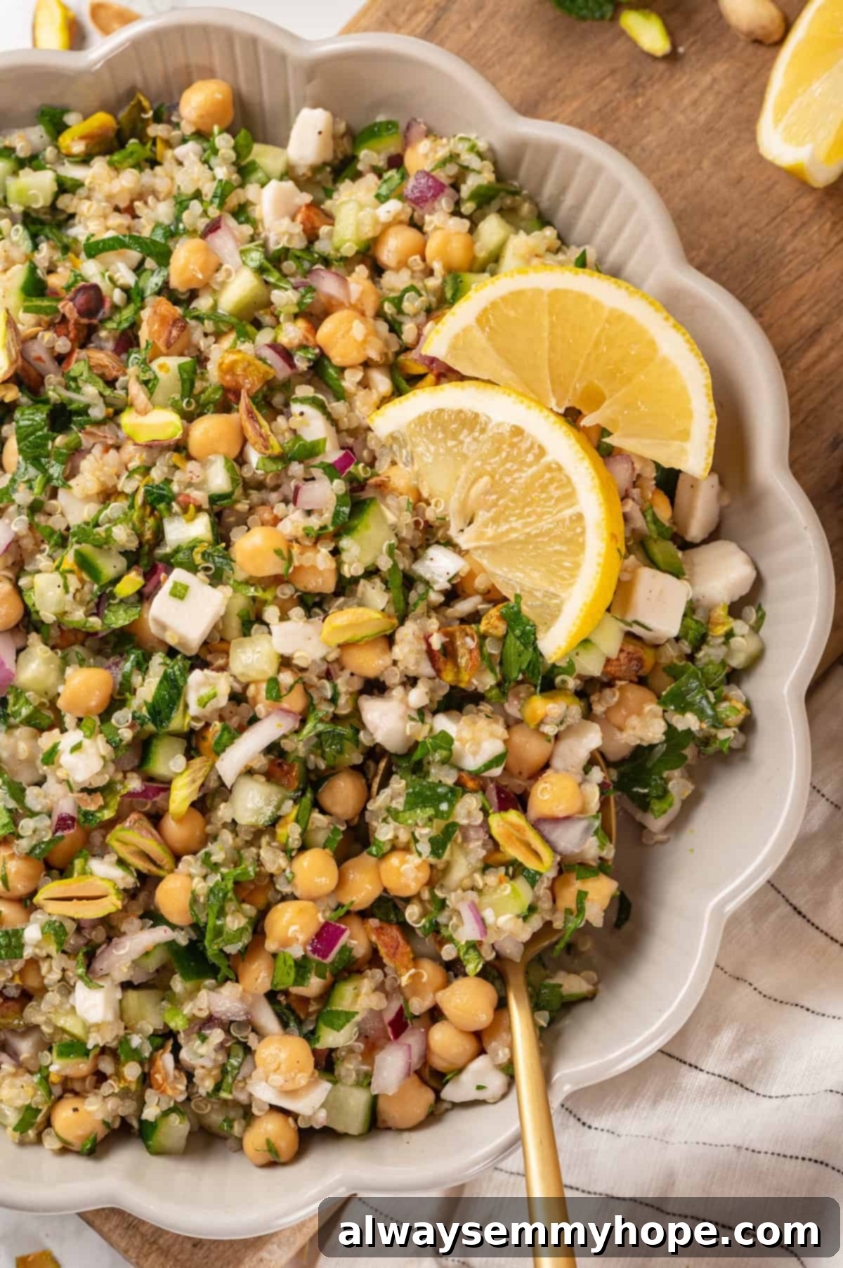 Overhead view of a vibrant vegan Jennifer Aniston salad in a serving bowl, garnished with fresh herbs and lemon wedges, ready to be enjoyed.